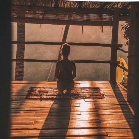 Frau sitzt und macht Morgen-Meditation