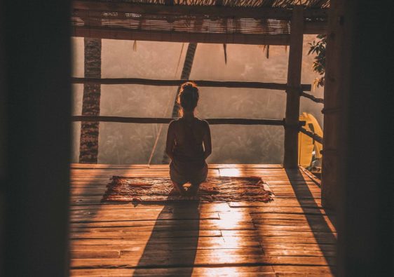 Frau sitzt und macht Morgen-Meditation